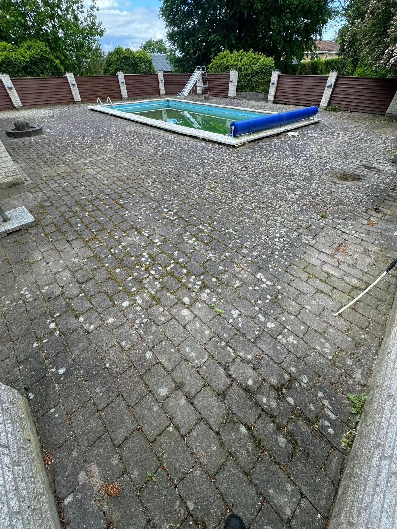 Udendørs swimmingpool med fliser og hegn i baghave