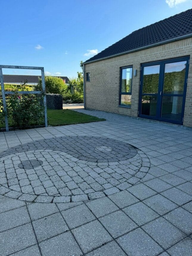 Moderne murstenshus med flisebelagt terrasse og have